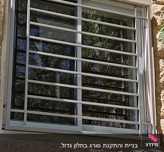 חלון עם סורגים מתכתיים על קיר אבן